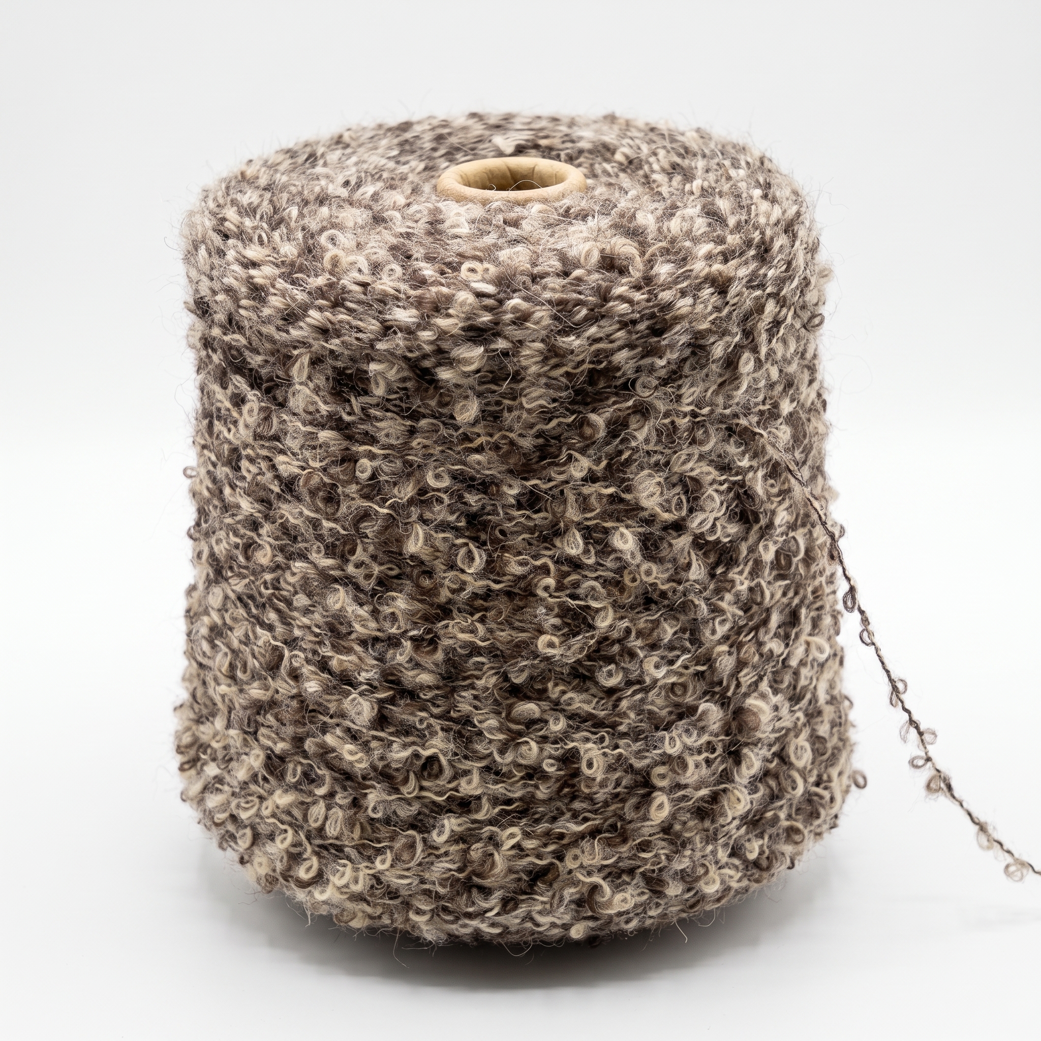 En spole med bouclegarn i brune og beige farger.