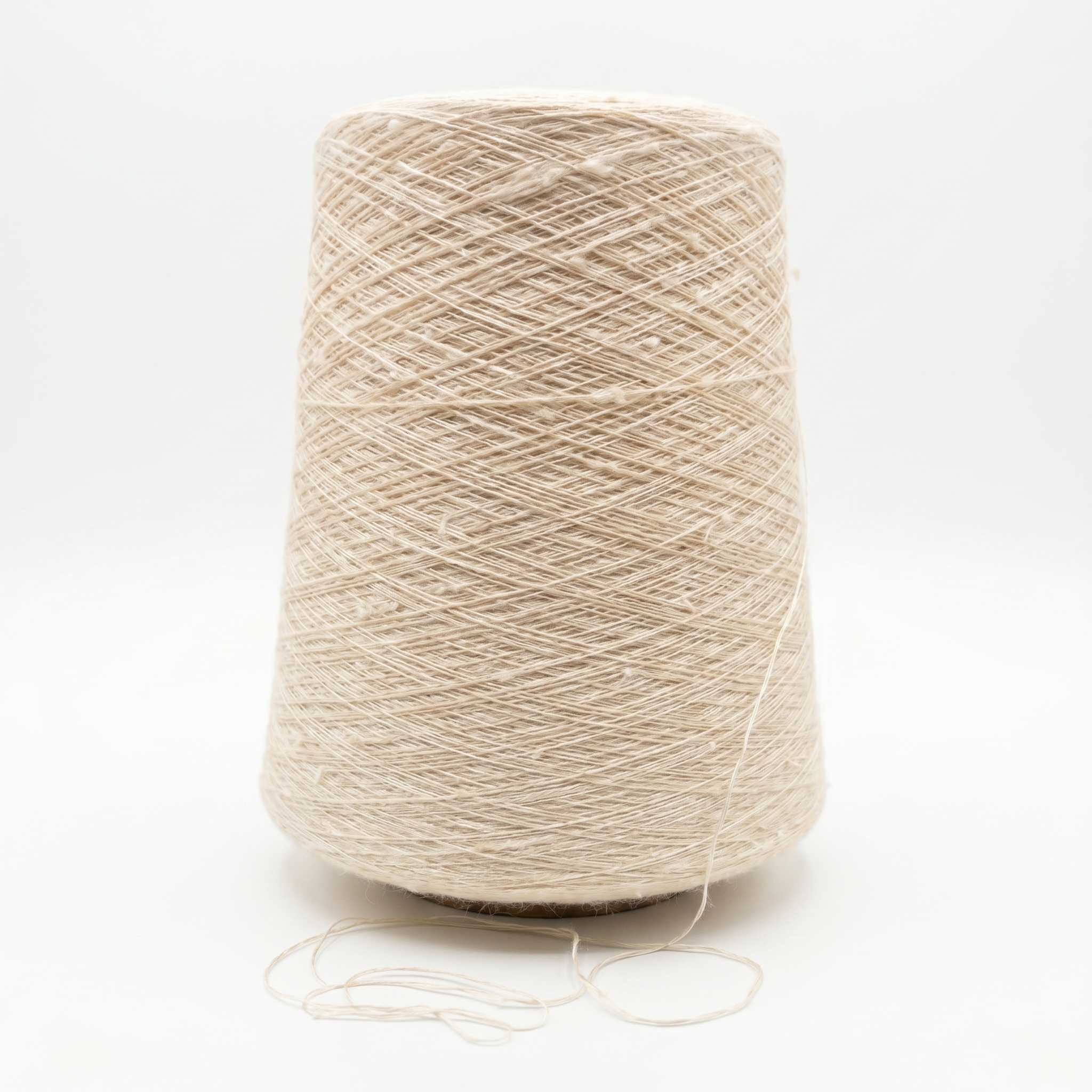 En stor spole med lyst beige, strukturert garn på en hvid bakgrunn.