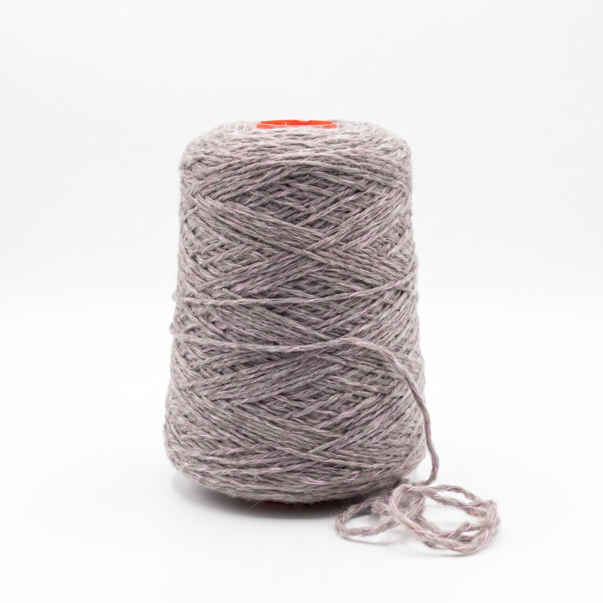 En stor spole med grått garn, spettet med lilla fibre, står på en hvit overflade.