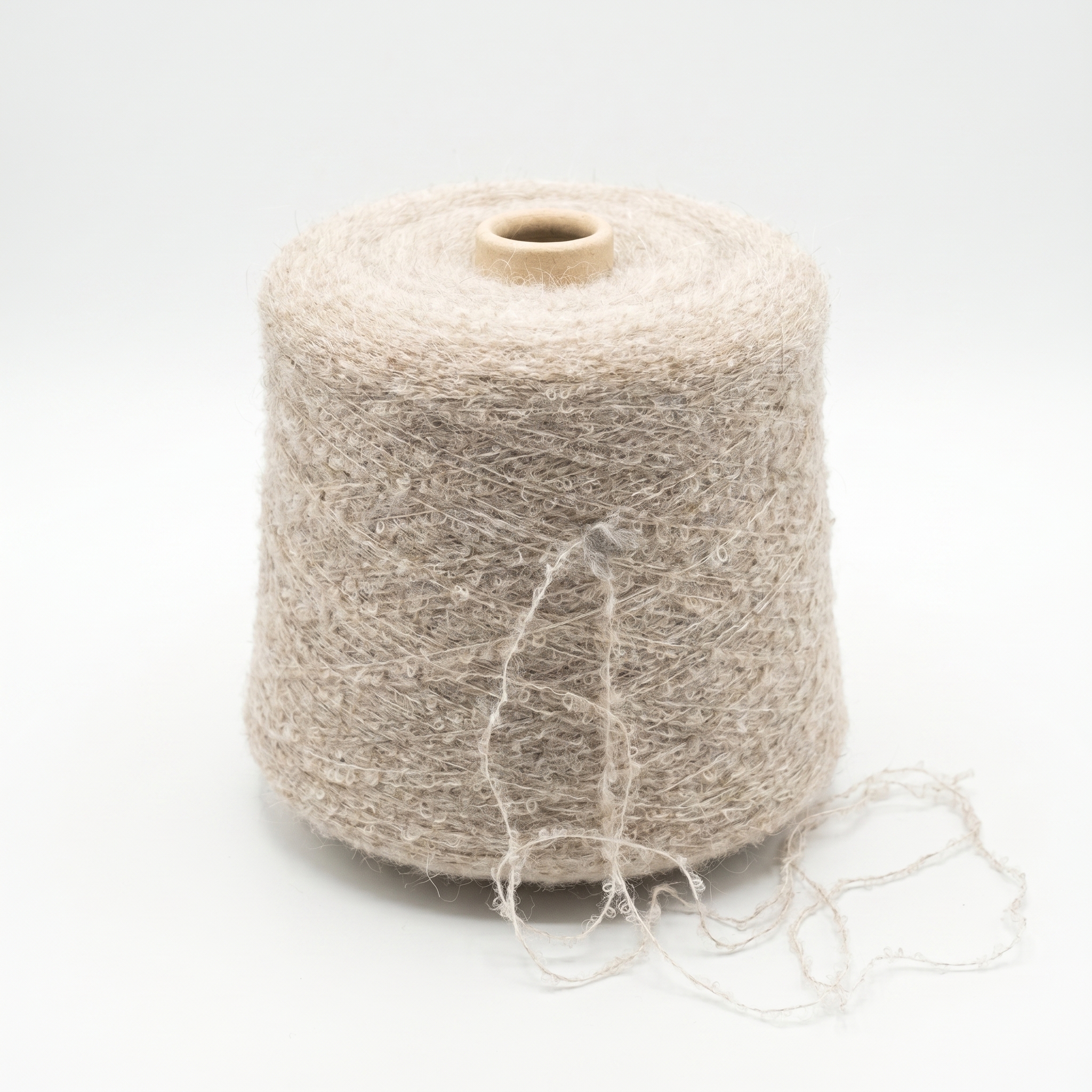 En stor spole med lyst beige, teksturert garn på en hvit bakgrunn.