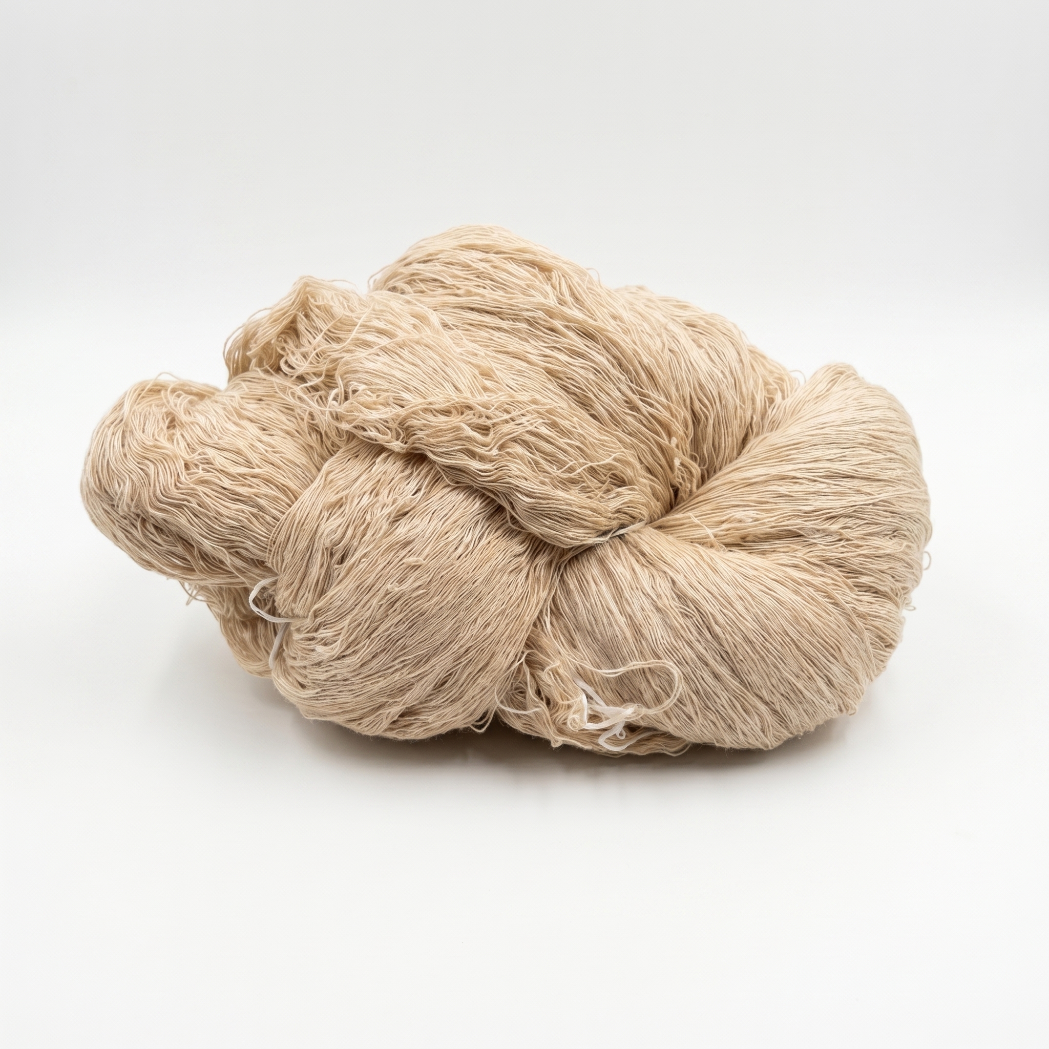 En hespe med lyst beige, fint garn på en hvit bakgrunn.