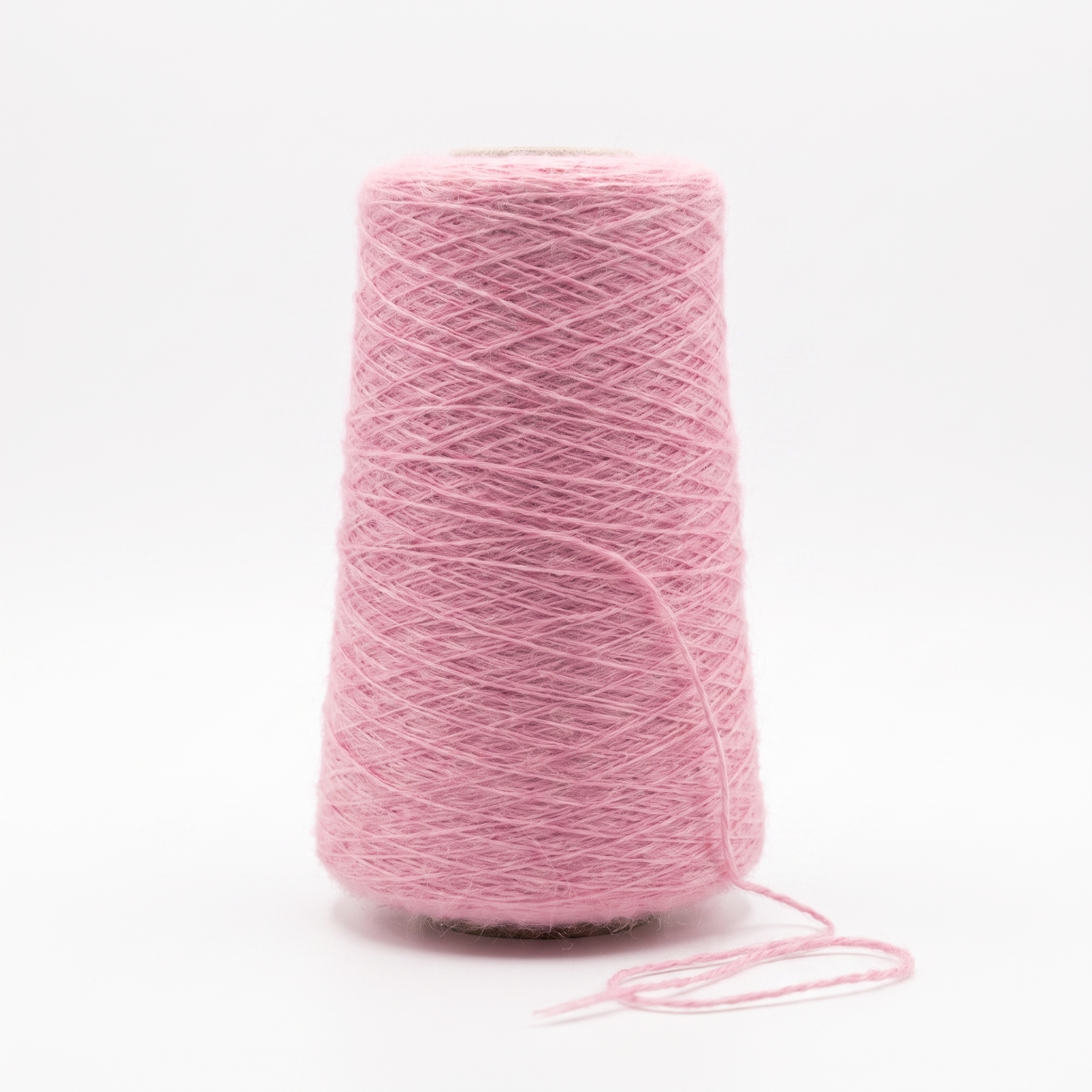 En stor spole med loddent rosa garn og en løs tråd på en hvit bakgrunn.