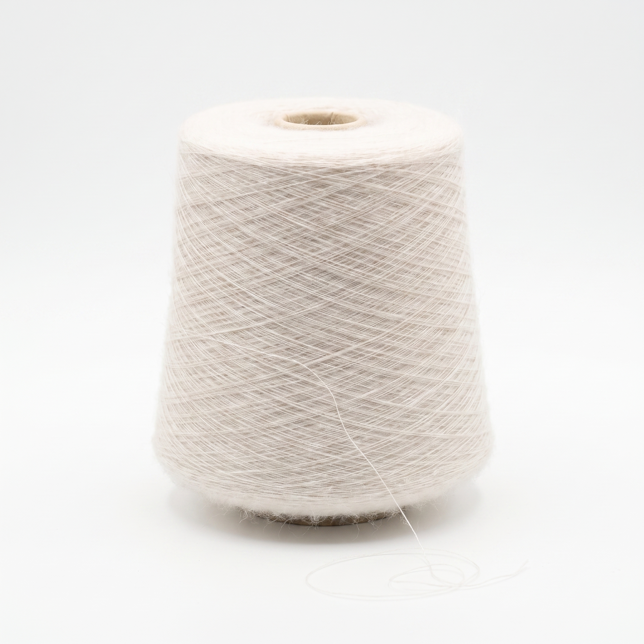 En spole med fint, lyst beige garn på en hvit bakgrunn.
