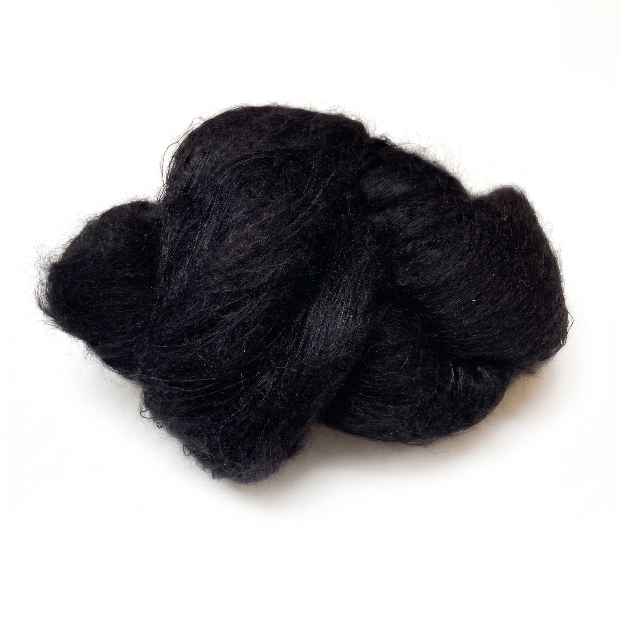 En løs mengde med sammenfiltrede svarte fibre på en hvit overflate.