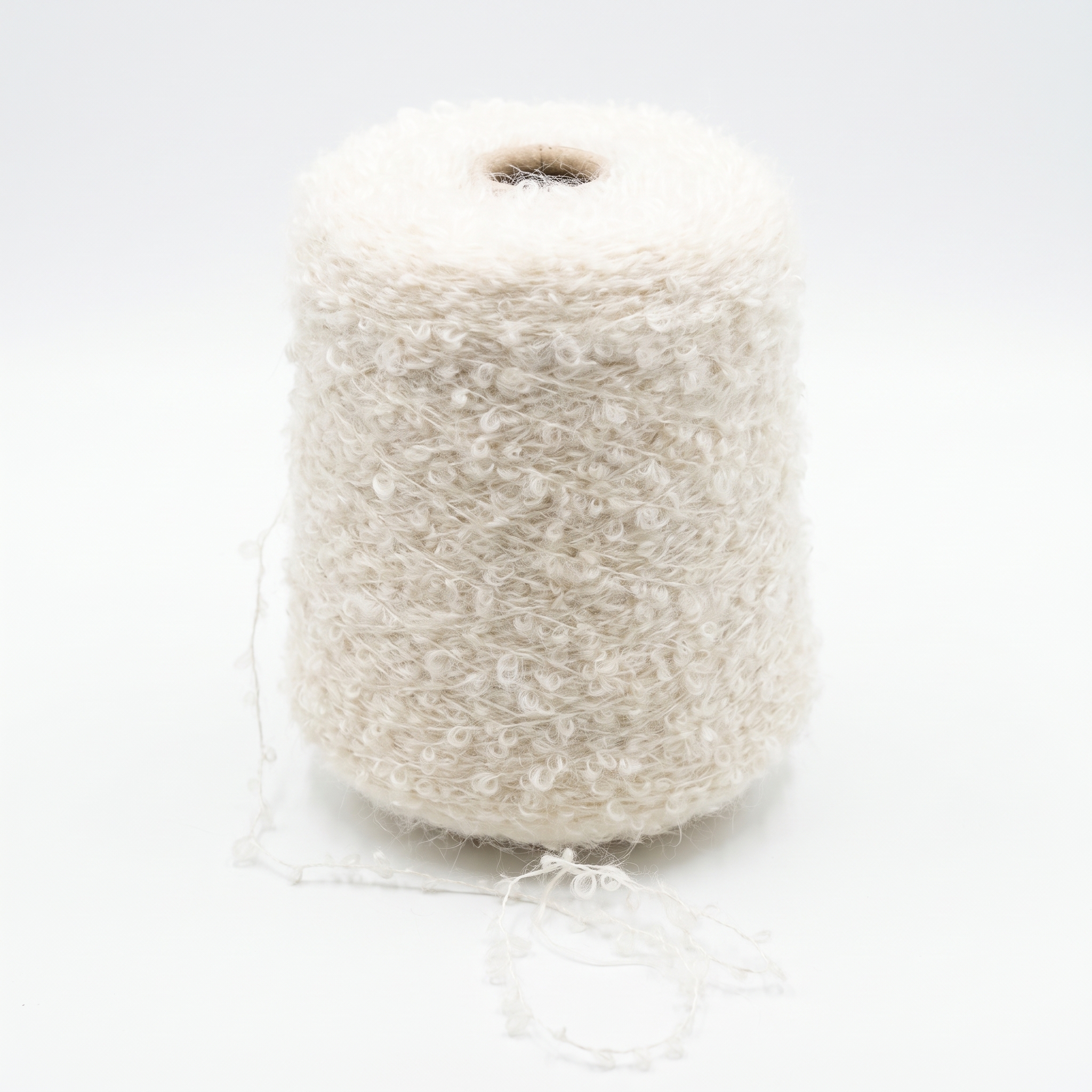 En stor spole med naturhvitt bouclégarn, hvor en løs tråd ligger ved bunnen på en hvit bakgrunn.