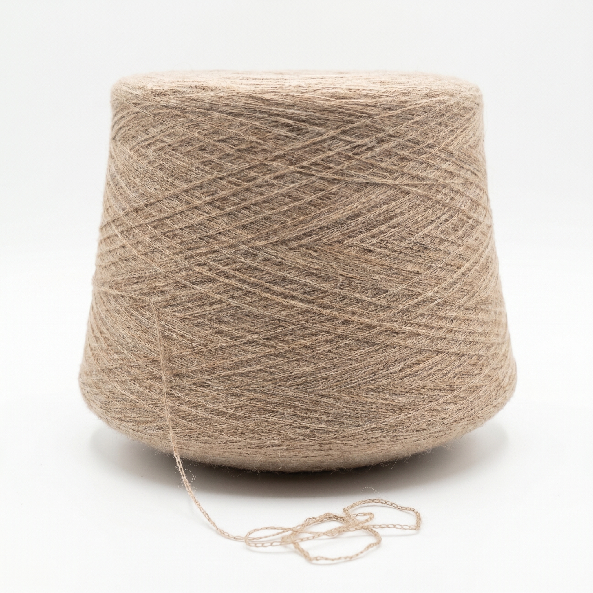 En stor spole med beige garn står på en hvit overflate med en løs tråd.