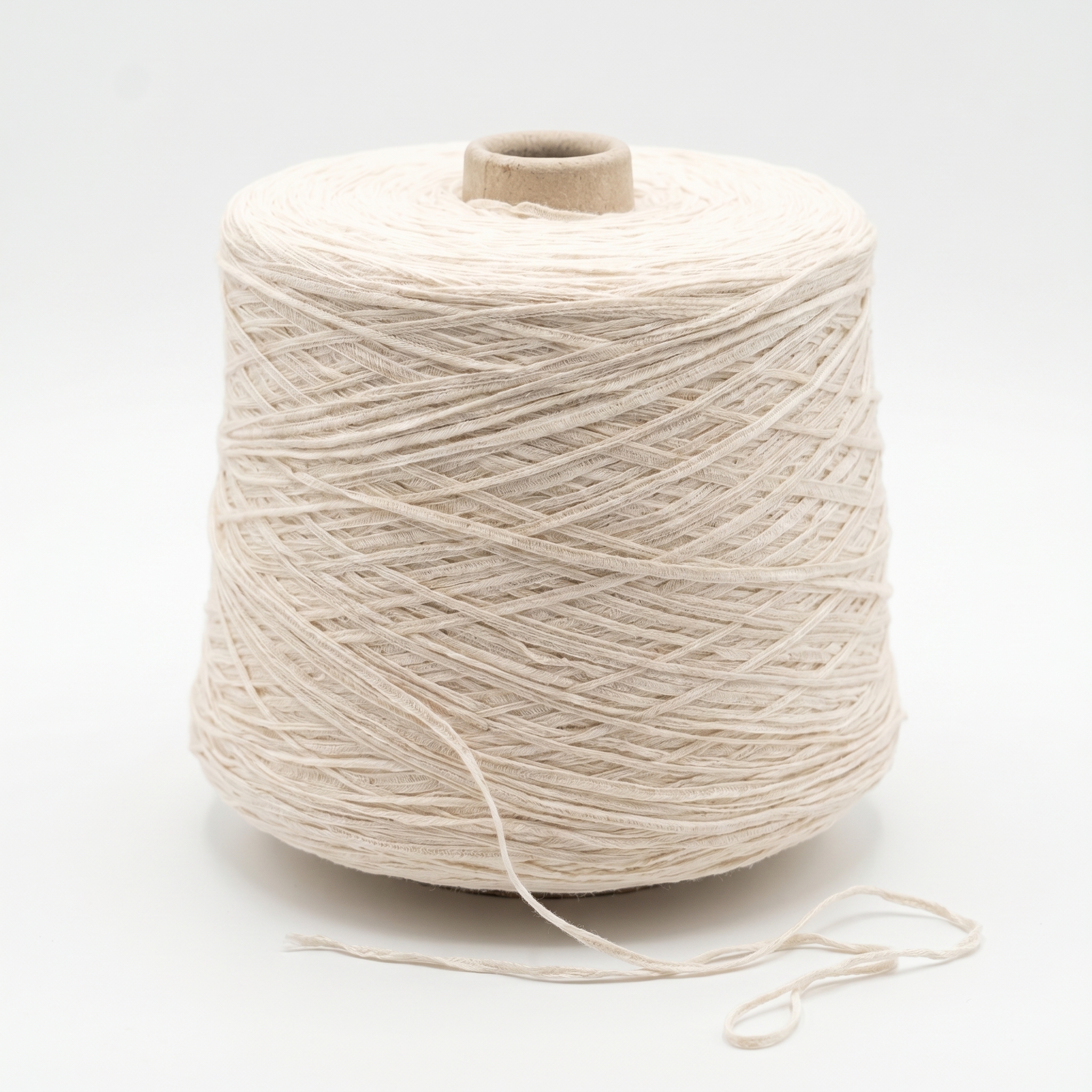 En stor spole av lyst beige garn er tett viklet, med en løs tråd hengende foran på en hvit bakgrunn.