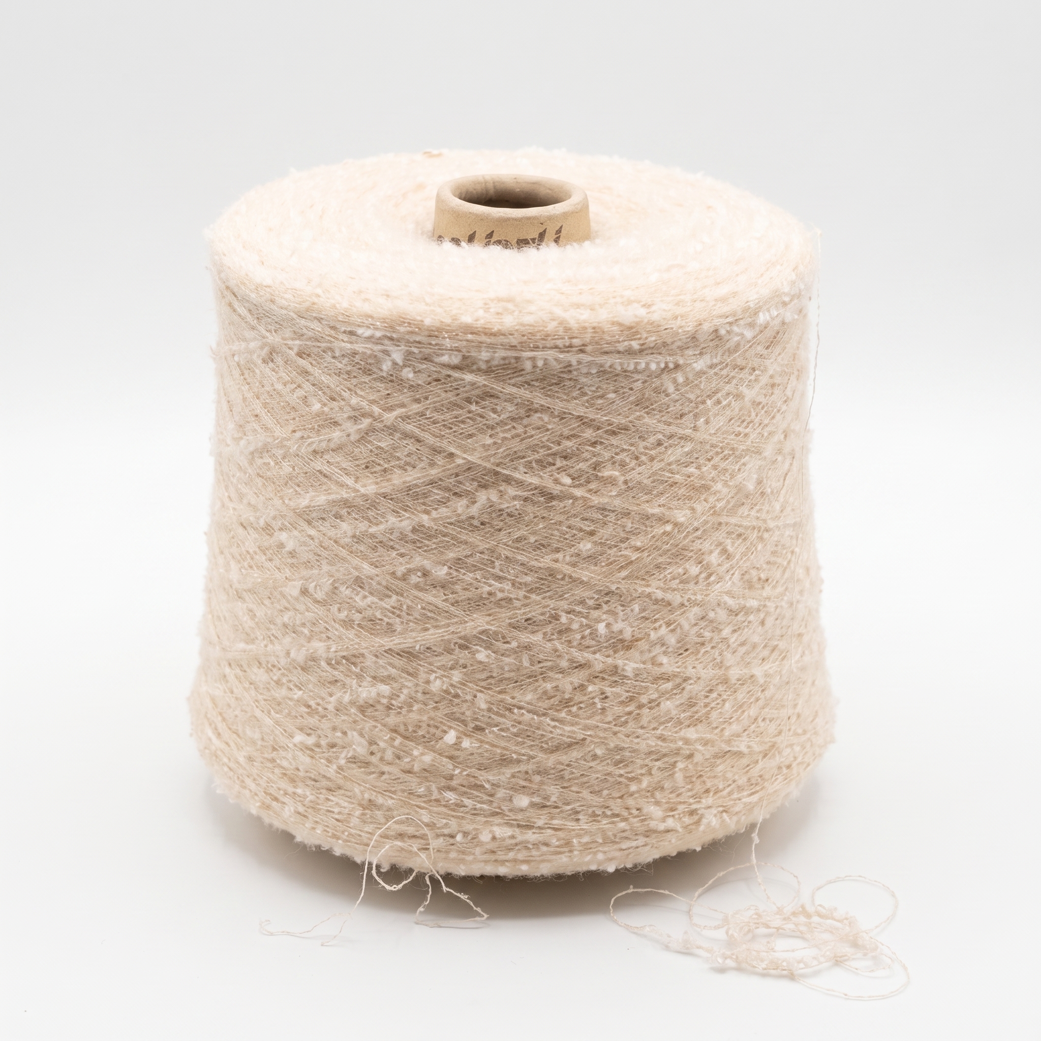 En stor spole med beige, strukturert garn på en lys bakgrunn.