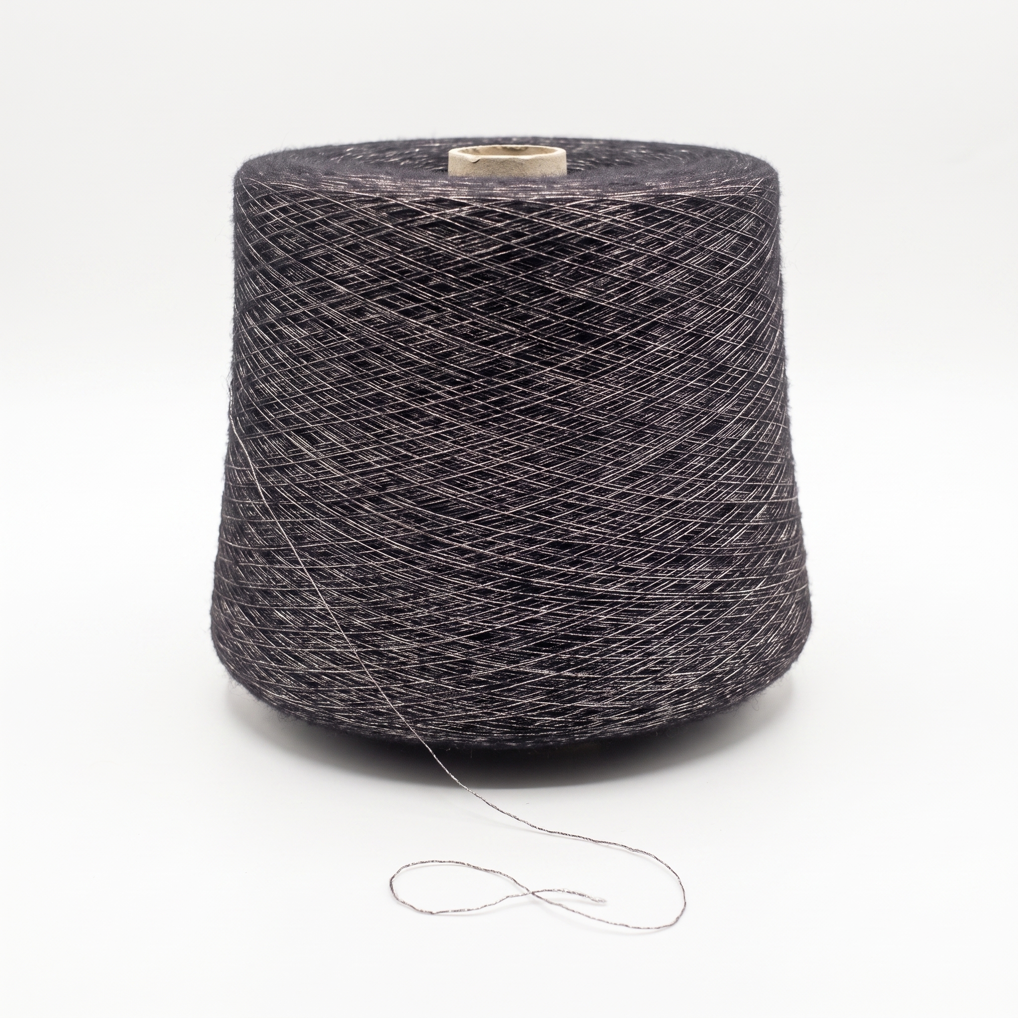 En stor spole med mørkegrått garn og en sølvfarget glittertråd, stående på en hvit overflate.