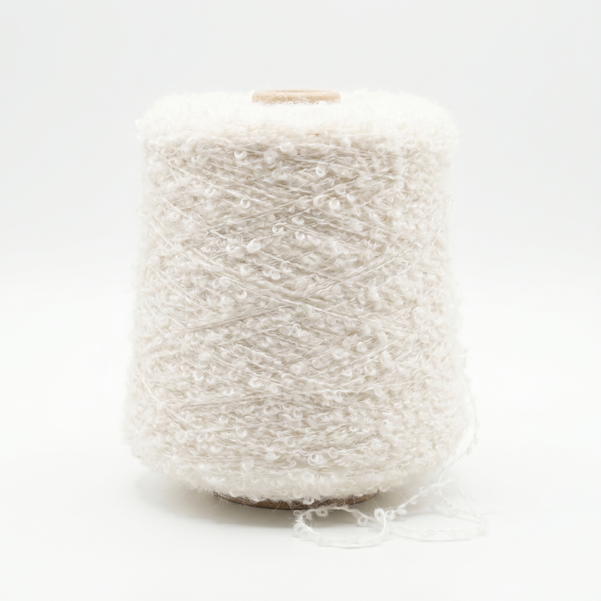 En spole med hvitt, mykt boucle-garn på en hvit bakgrunn.