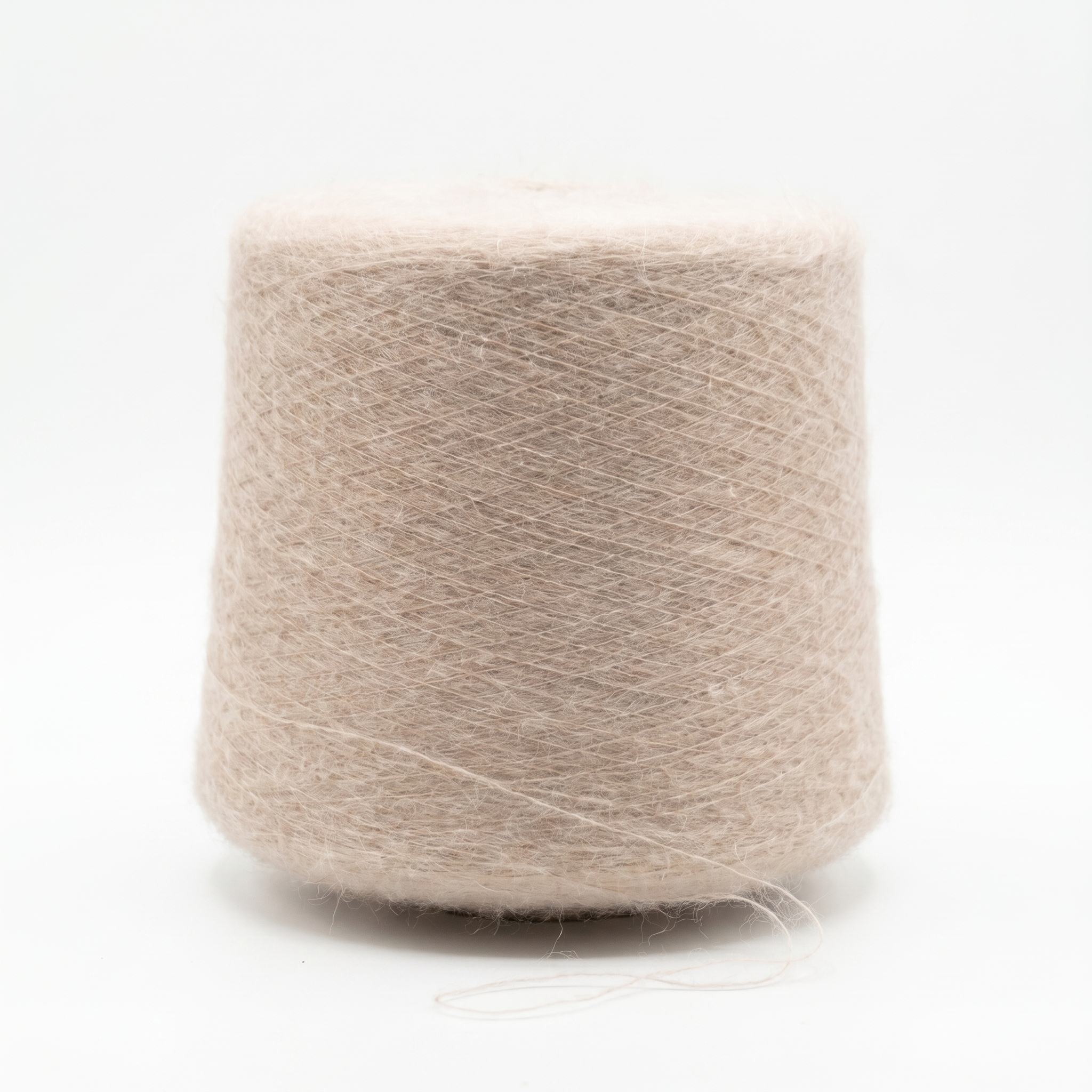 En stor spole med lyst beige, hårete garn på en hvit bakgrunn.