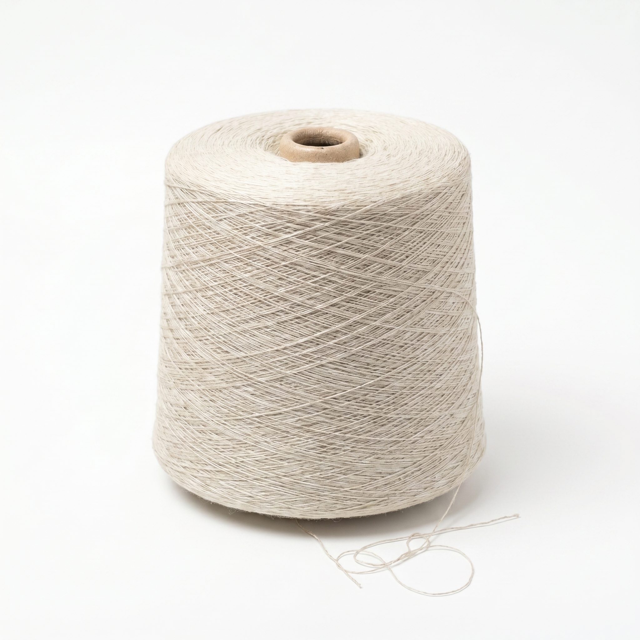 En stor spole med lyst beige garn på hvit bakgrunn.