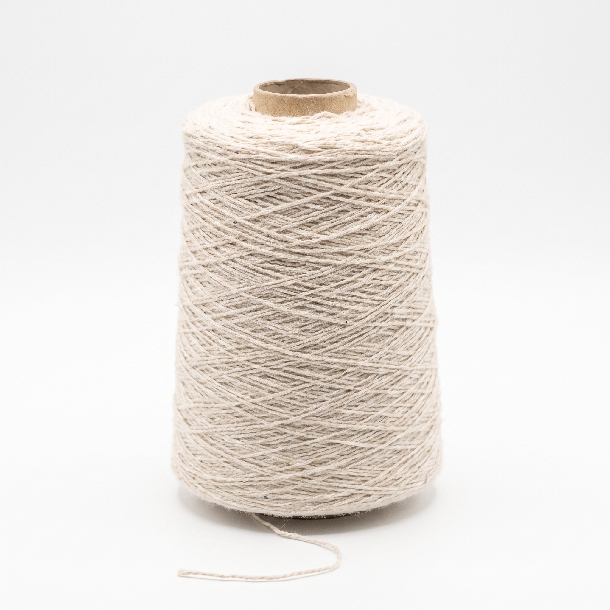 En stor spole med lyst, beige garn mot en hvit bakgrunn.