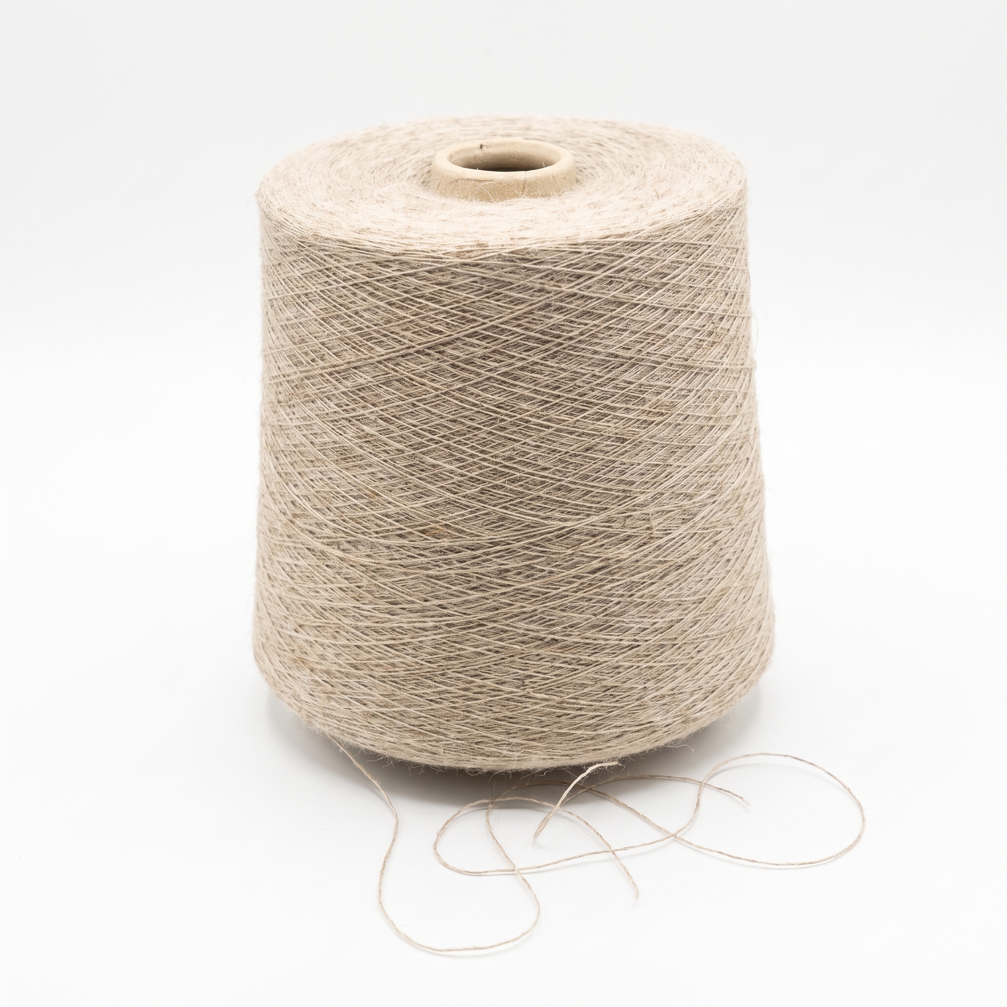 En stor spole med lyst beige garn står på en hvit bakgrunn med litt løs tråd nederst.