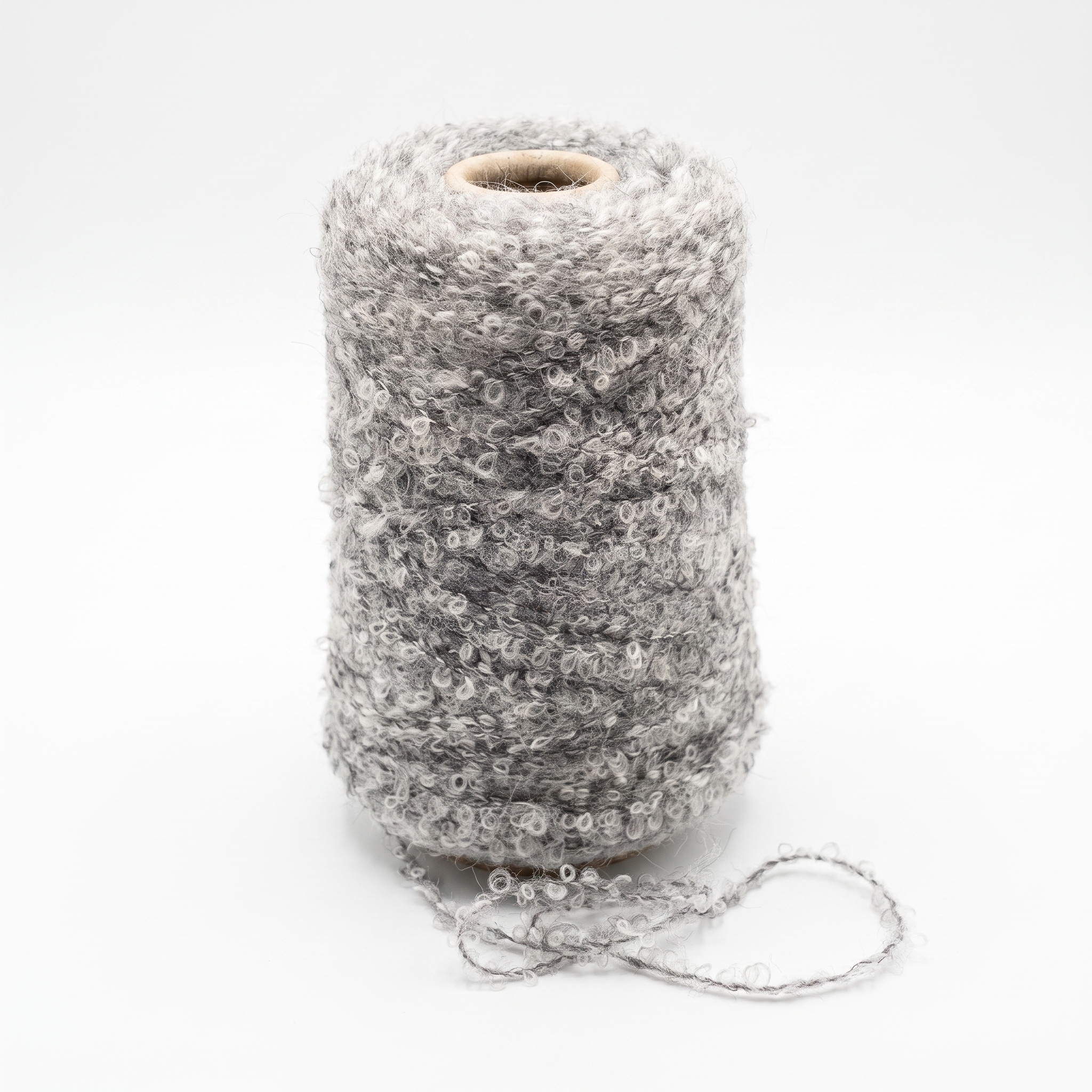 En spole med grått, løkket bouclé-garn på en hvit bakgrunn.