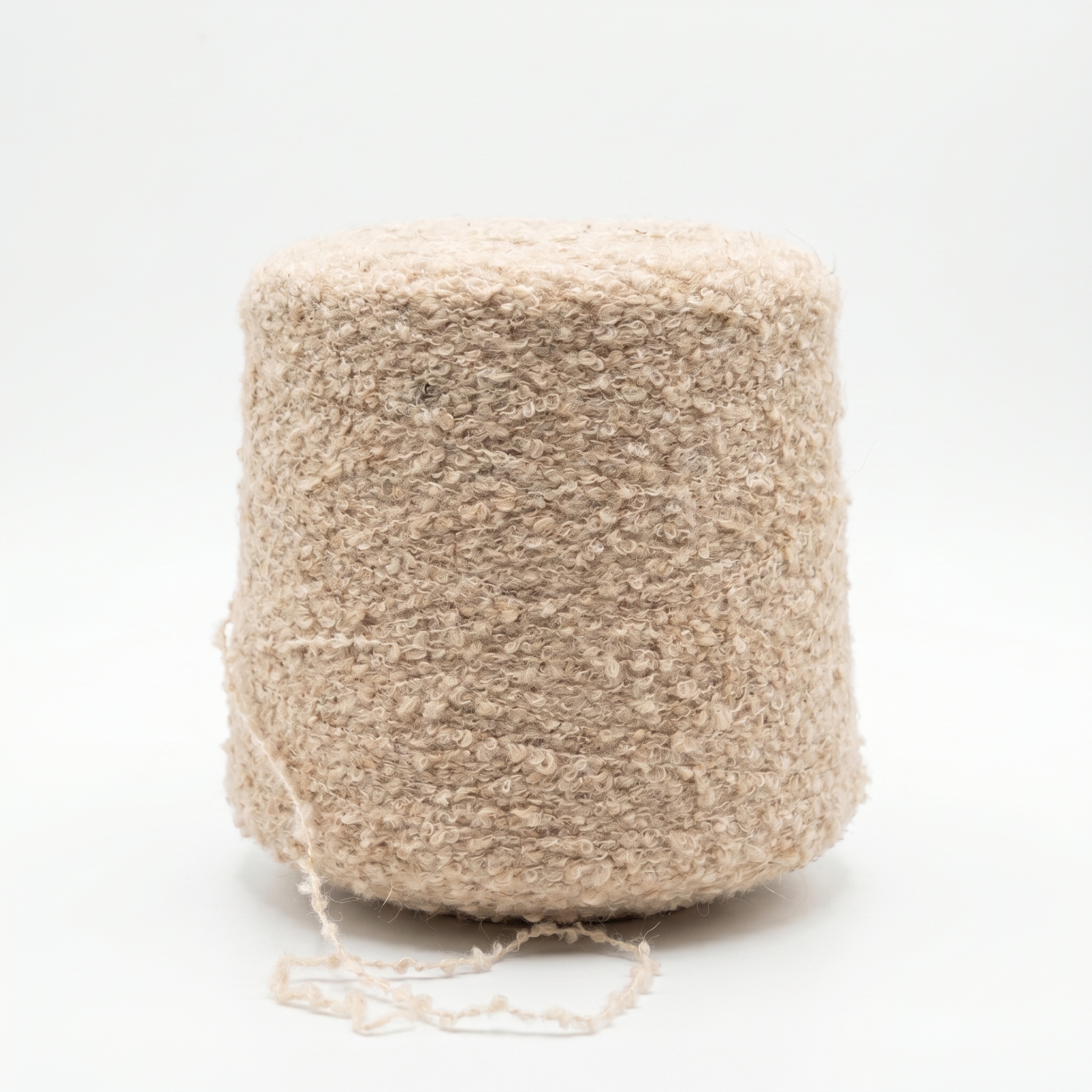 Et bilde av beige, teksturert garn viklet på en stor spole, med en løs tråd i bunnen mot en hvit bakgrunn.