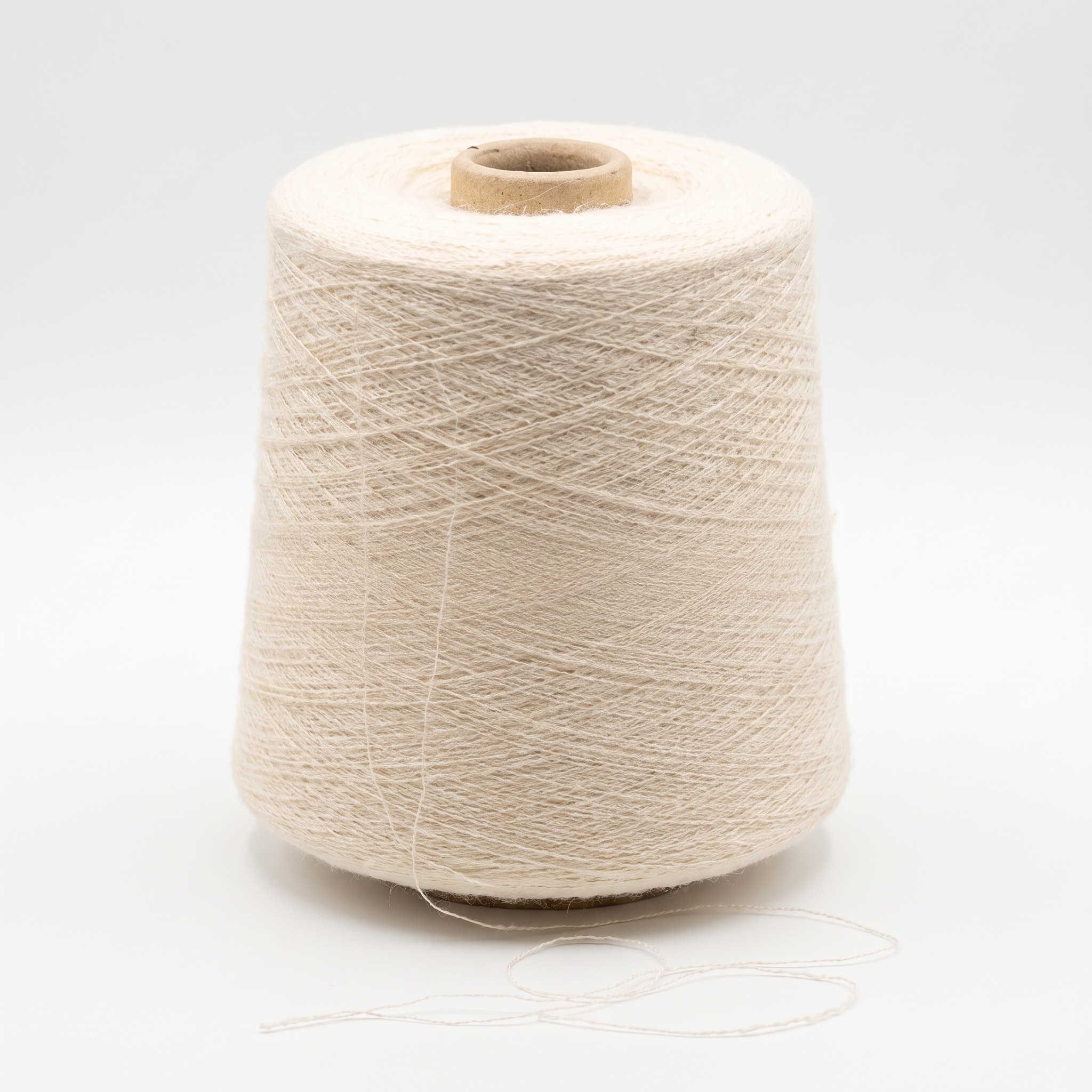 En stor spole med lyst beige garn og en løs tråd.
