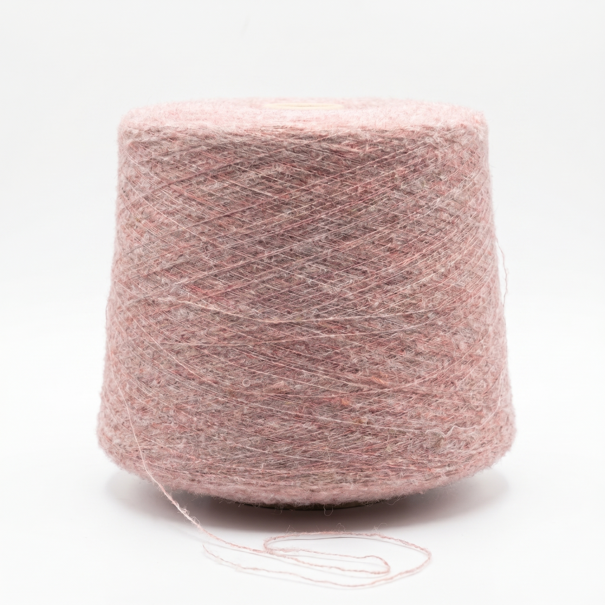 En spole med spettet rosa garn og en løs tråd foran på en hvit bakgrunn.