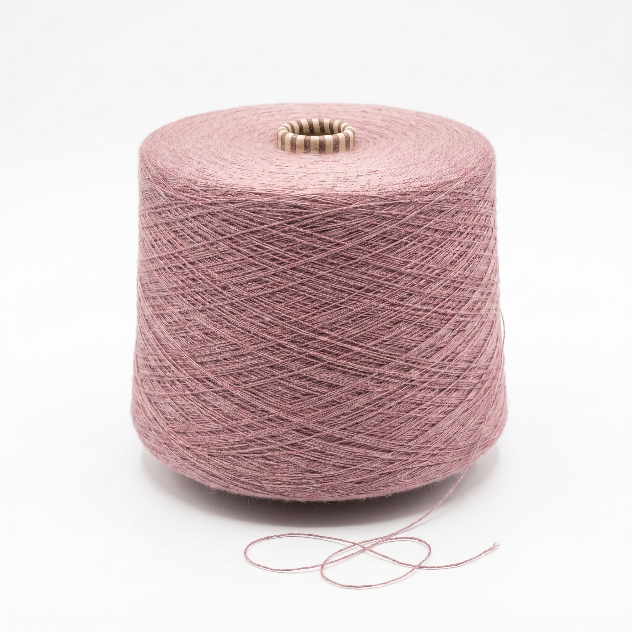 En stor spole med støvete rosa garn på hvit bakgrunn, med en løs trådende i bunnen.