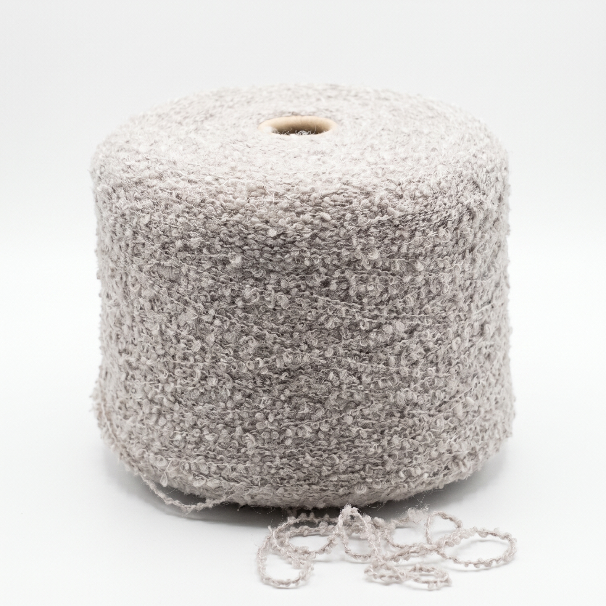 En stor spole med beige bouclé-garn og litt garn ved bunnen.