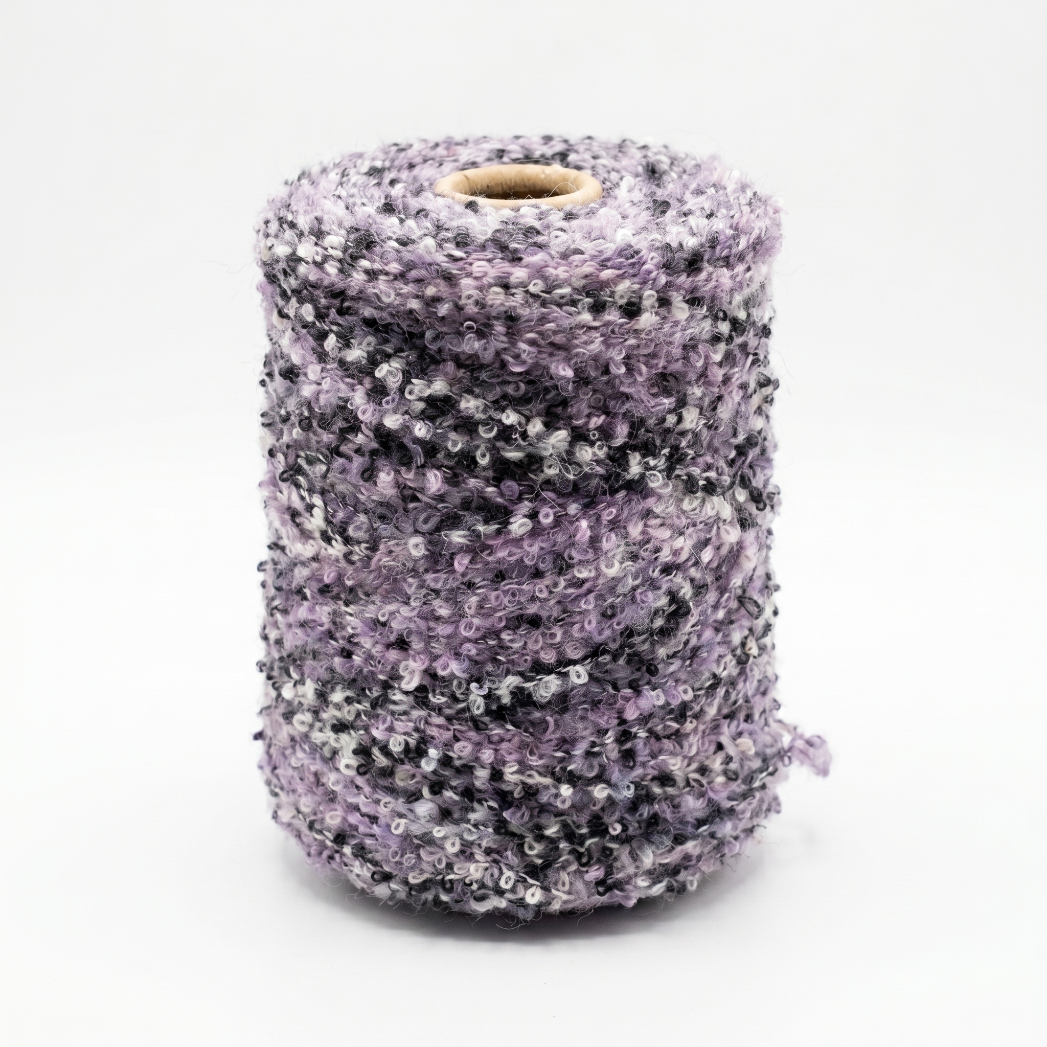 En spole med flerfarget boucle-garn i lilla, svarte, grå og hvite toner.