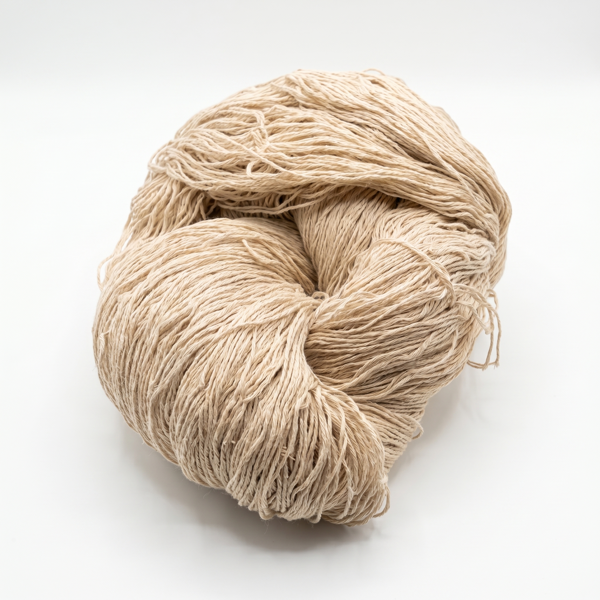 Et løst oppviklet fedd av lyst beige tråd på en hvit bakgrunn.