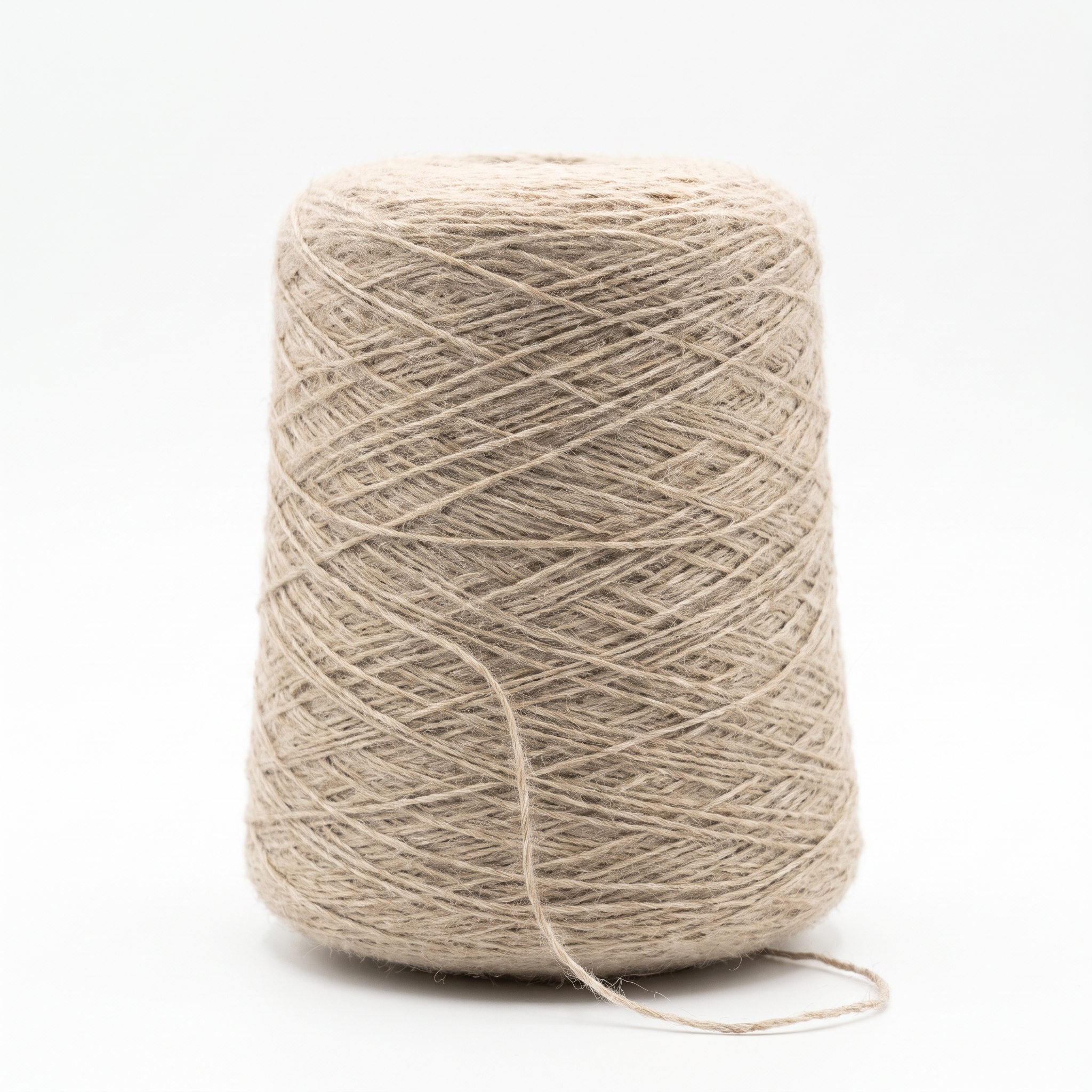 En spole med beige, grovt garn på en hvit bakgrunn.