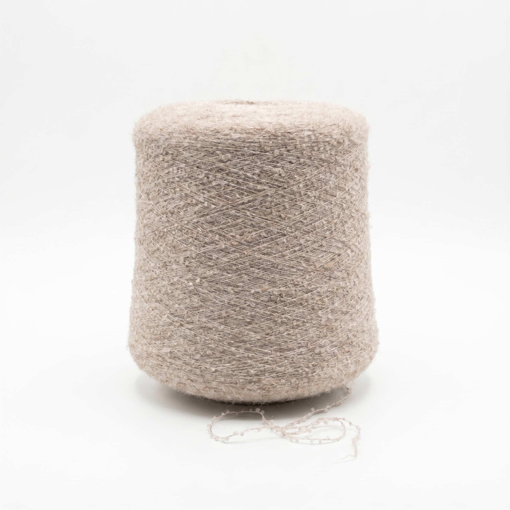 En stor spole med lyst beige, strukturert garn på hvit bakgrunn, med en løs tråd liggende foran.