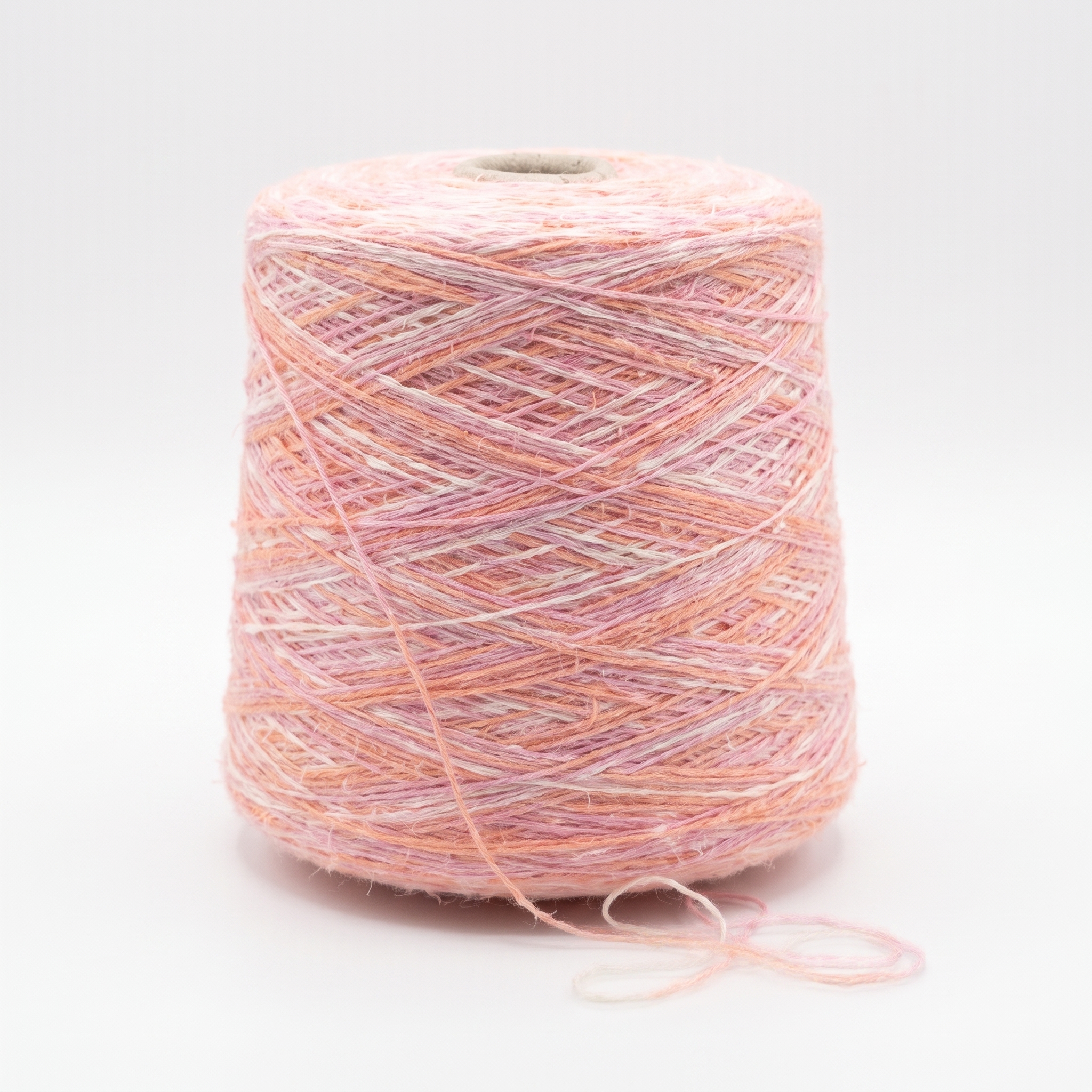 En spole med melert garn i rosa, ferskenfargede og hvite nyanser.