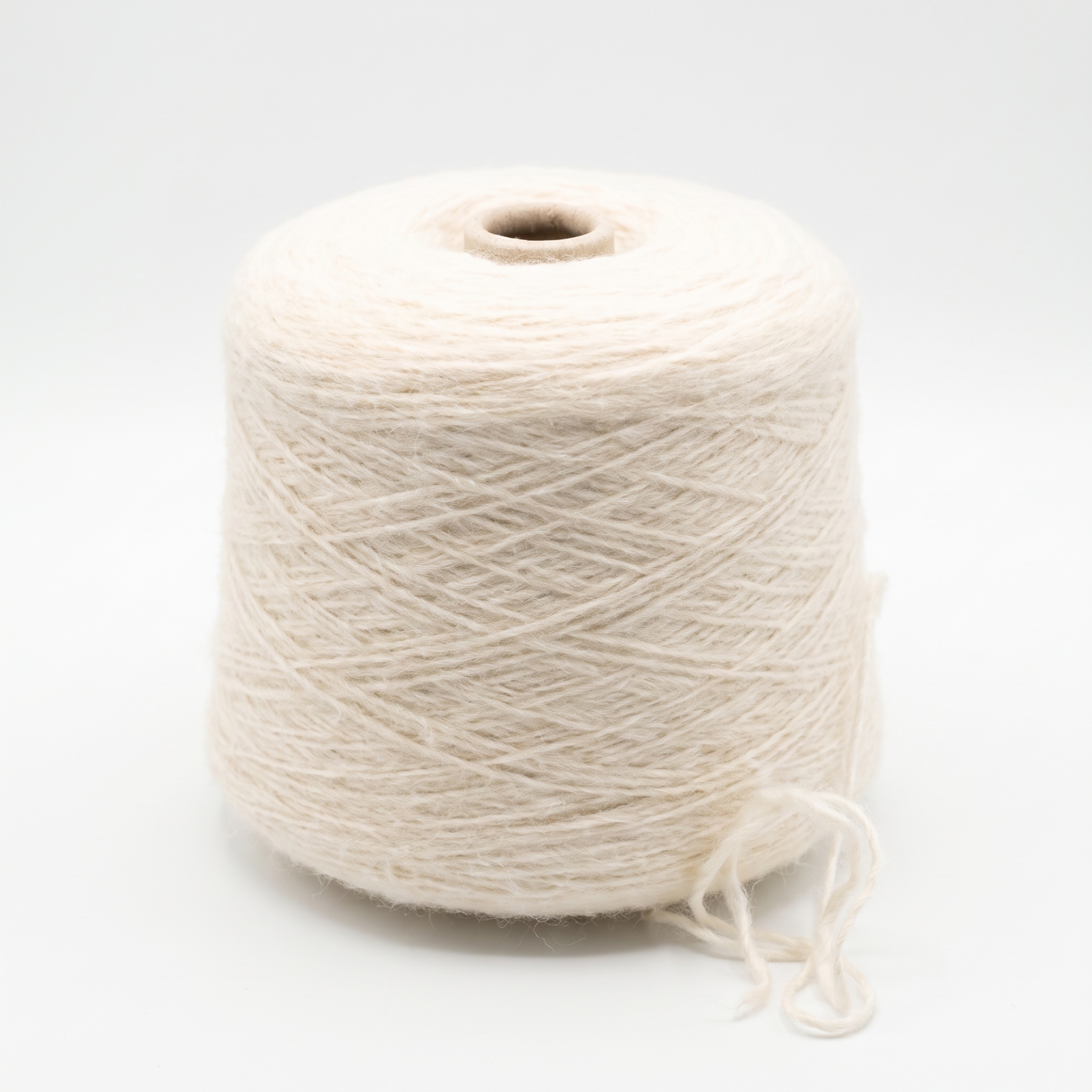 En spole med lyst beige garn på en hvit bakgrunn.