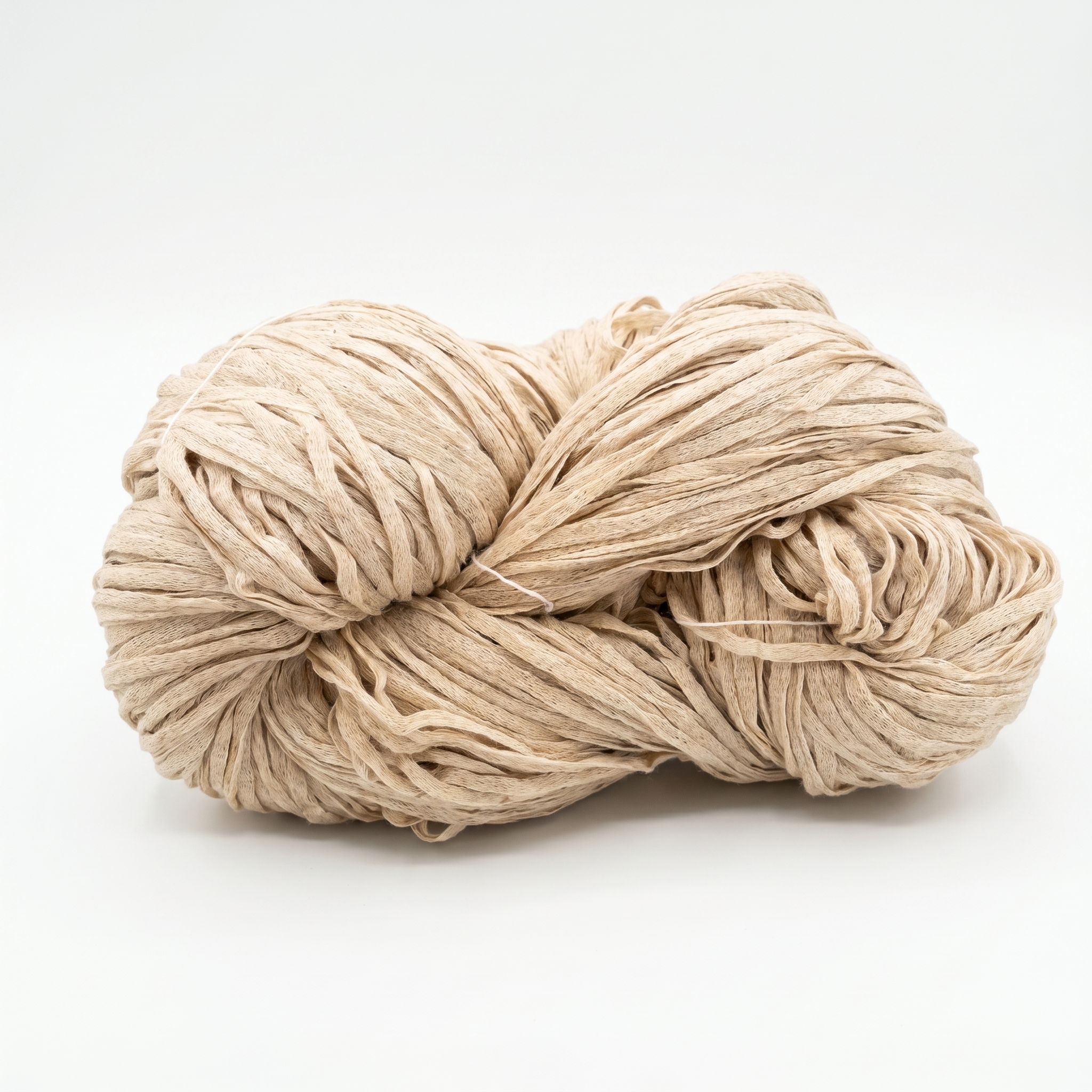En hesp av beige garn som ligner raffia, mot en hvit bakgrunn.