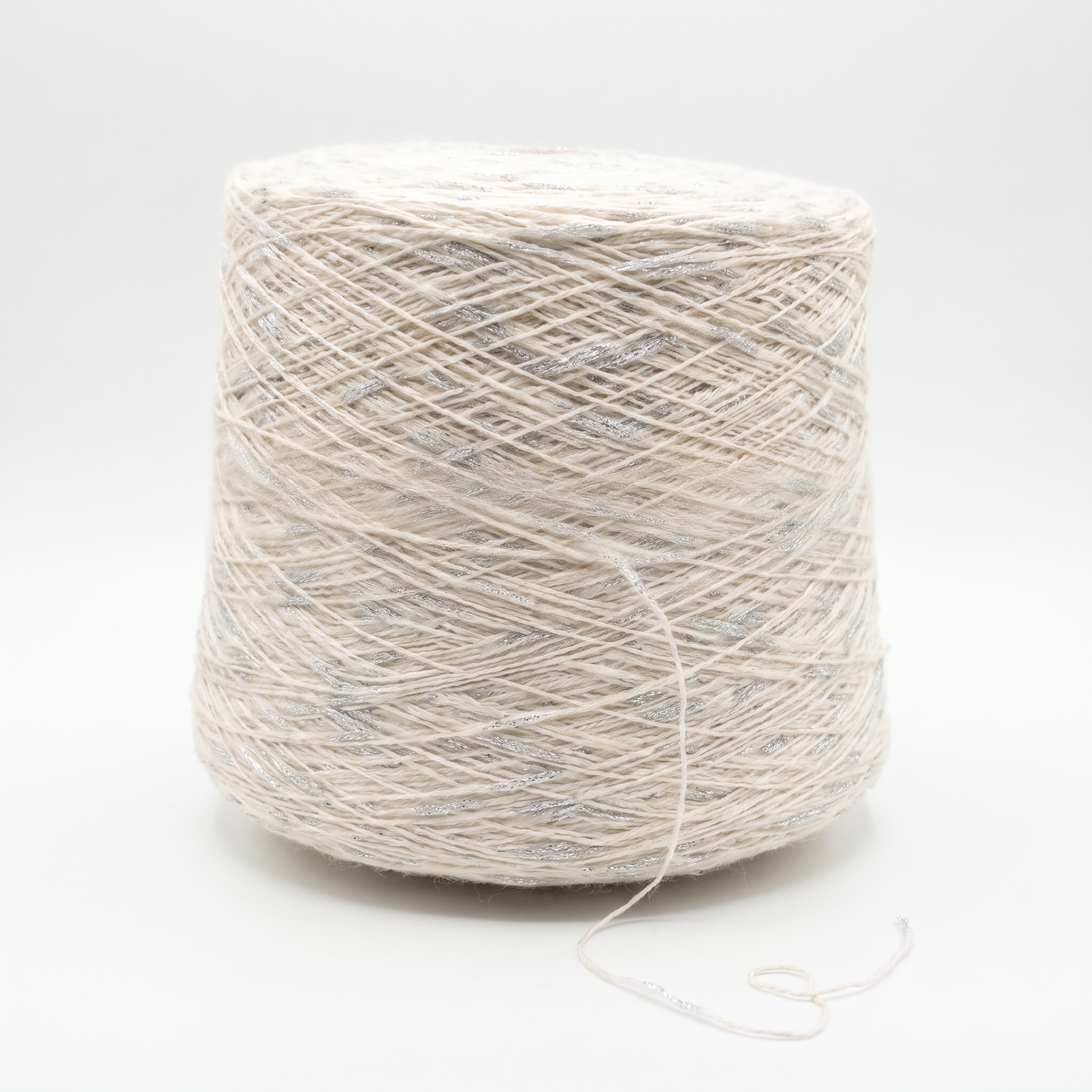 En stor spole med lyst beige garn og sølvglimmertråder, på en hvit bakgrunn.