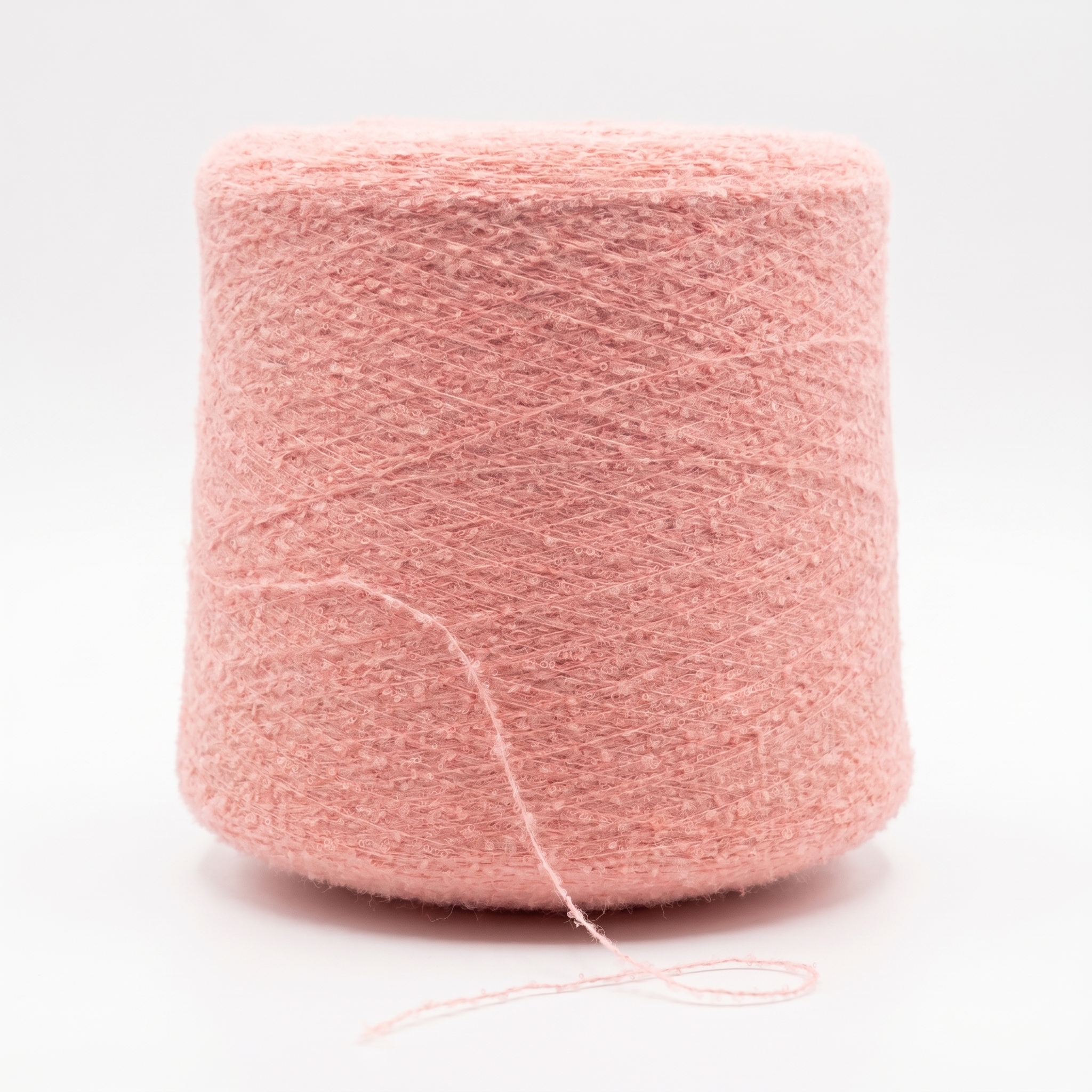 En stor spole med rosa, teksturert garn på en hvit bakgrunn.