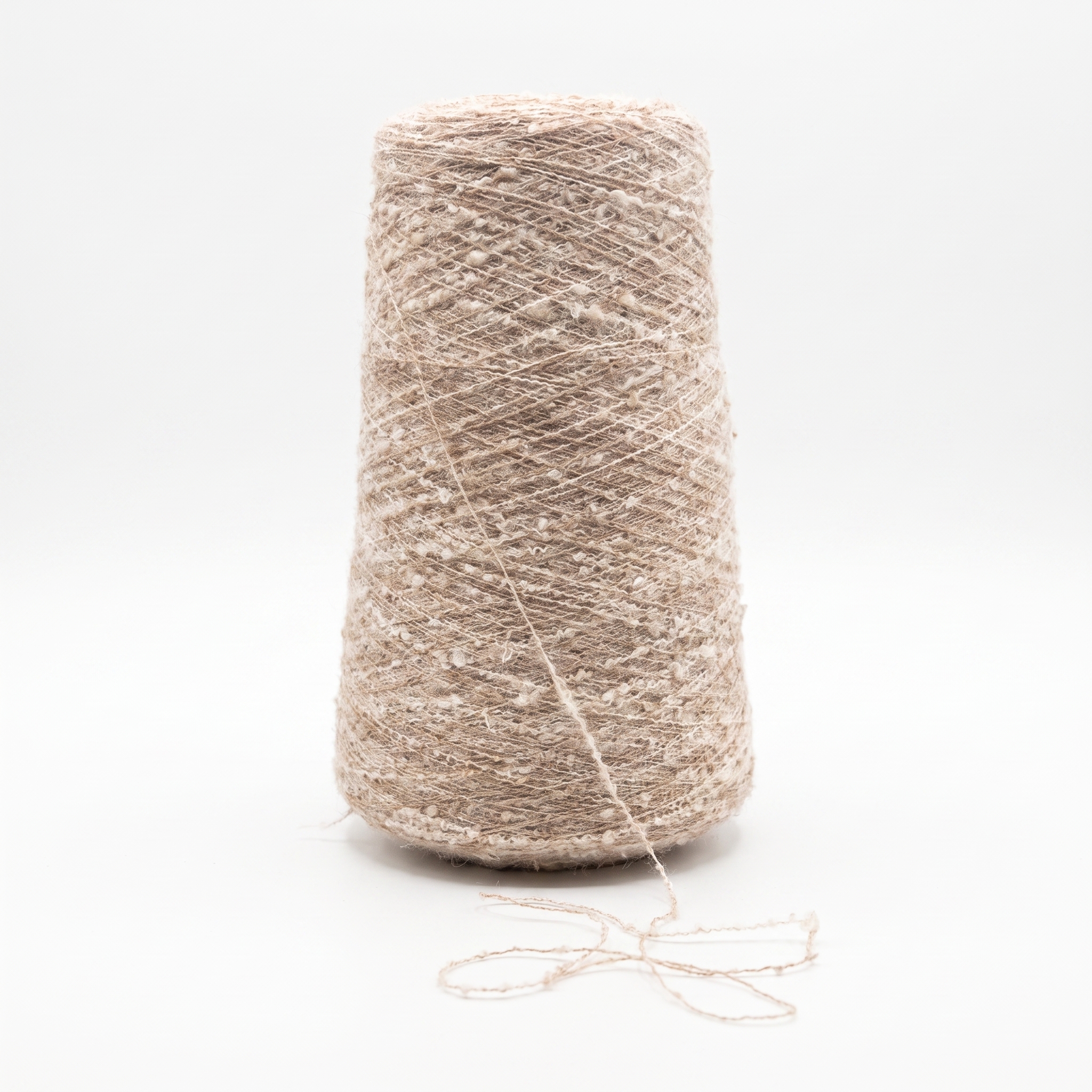 En spole med beige, strukturert garn på en hvit bakgrunn.