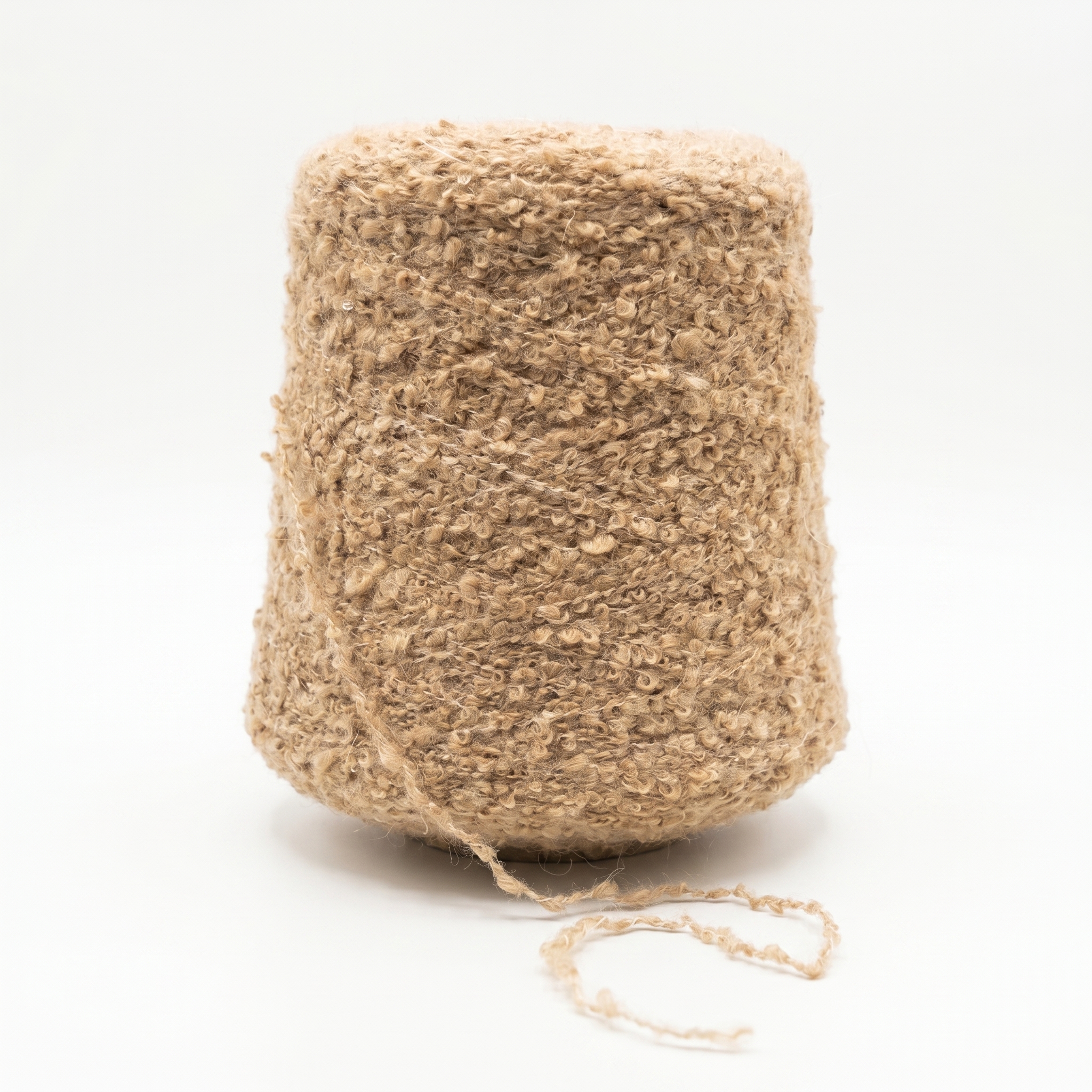 En stor spole med beige bouclégarn mot en hvit bakgrunn.