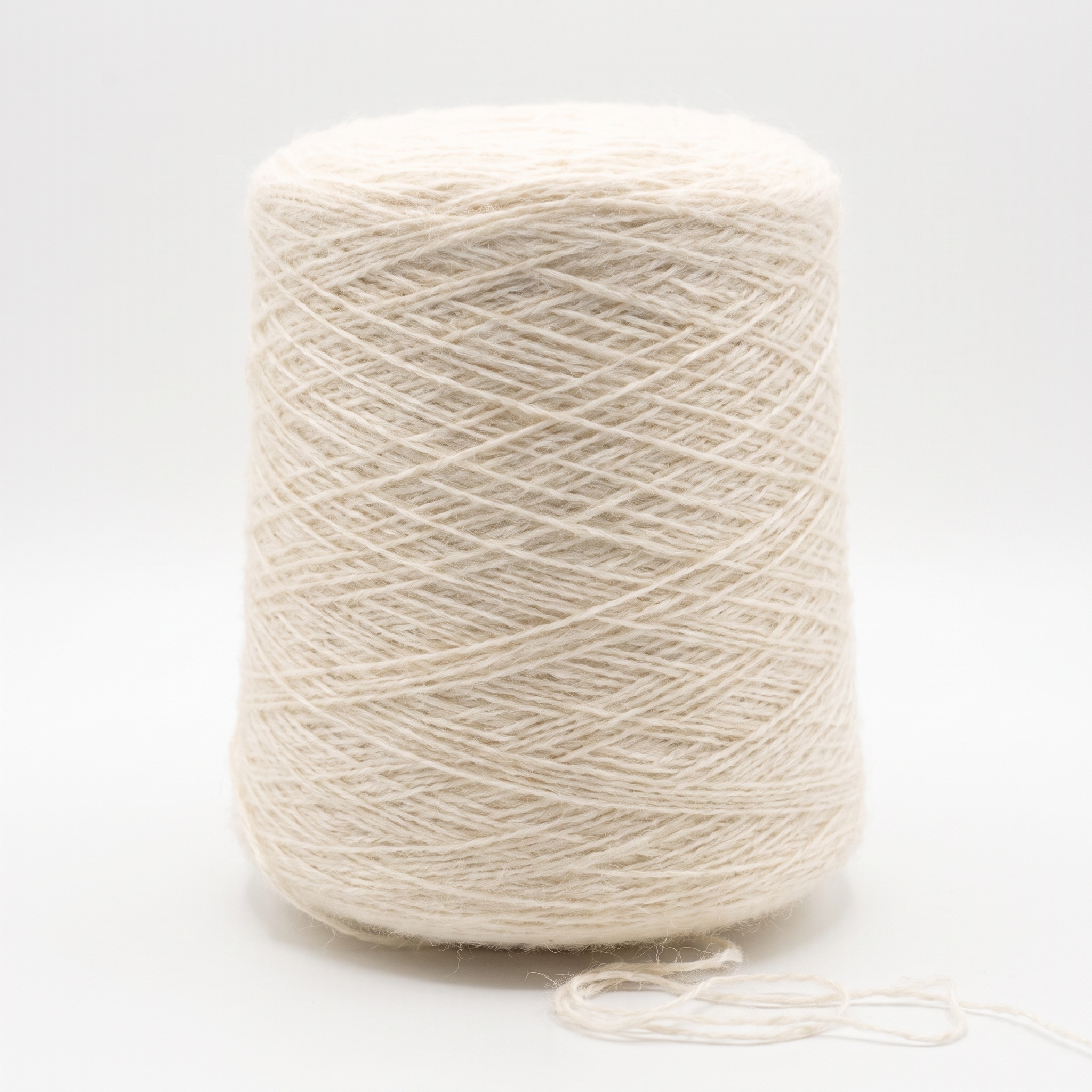 En stor spole med lyst beige garn, og en liten ende av tråden ligger løst ved bunnen.