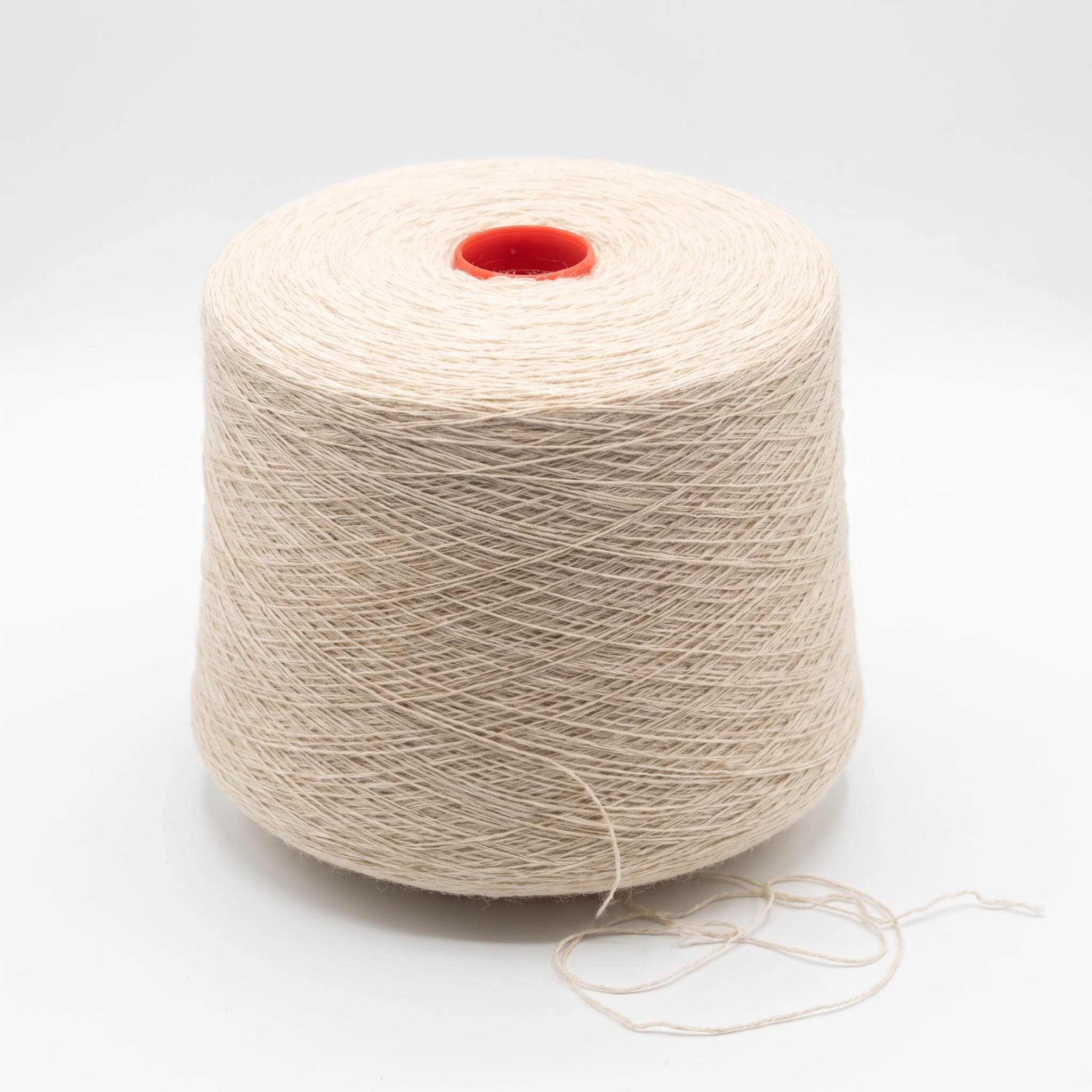 En stor spole med lyst beige garn står på en hvit overflate.